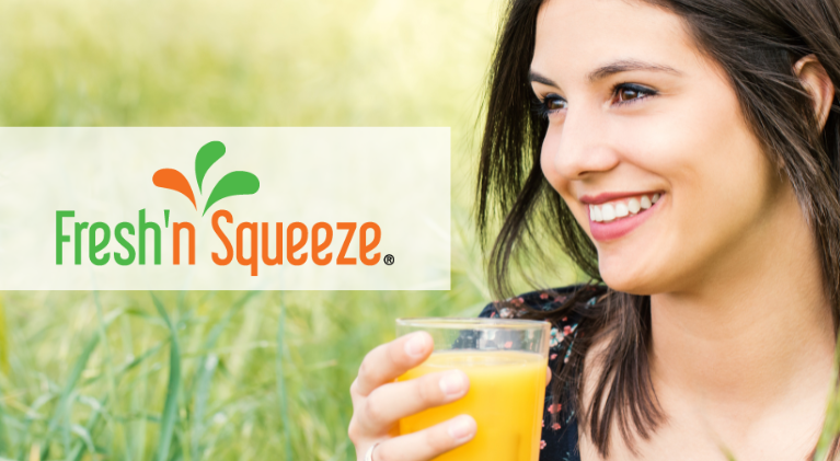 woman holding glass of freshly squeezed orange juice with logo overlay of JBT Fresh'n Squeeze